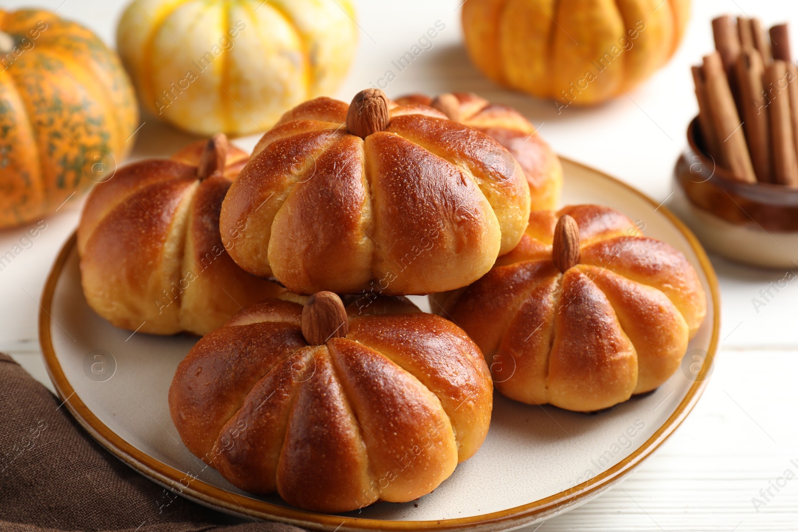 Photo of Tasty pumpkin shaped buns and ingredients on white wooden table, closeup