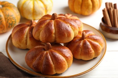 Photo of Tasty pumpkin shaped buns and ingredients on white wooden table, closeup