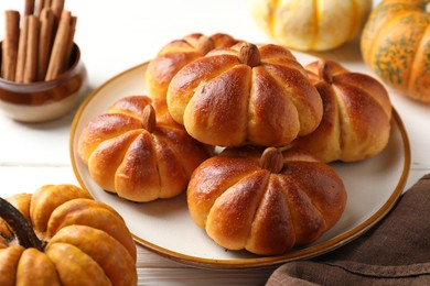 Photo of Tasty pumpkin shaped buns and ingredients on white wooden table, closeup