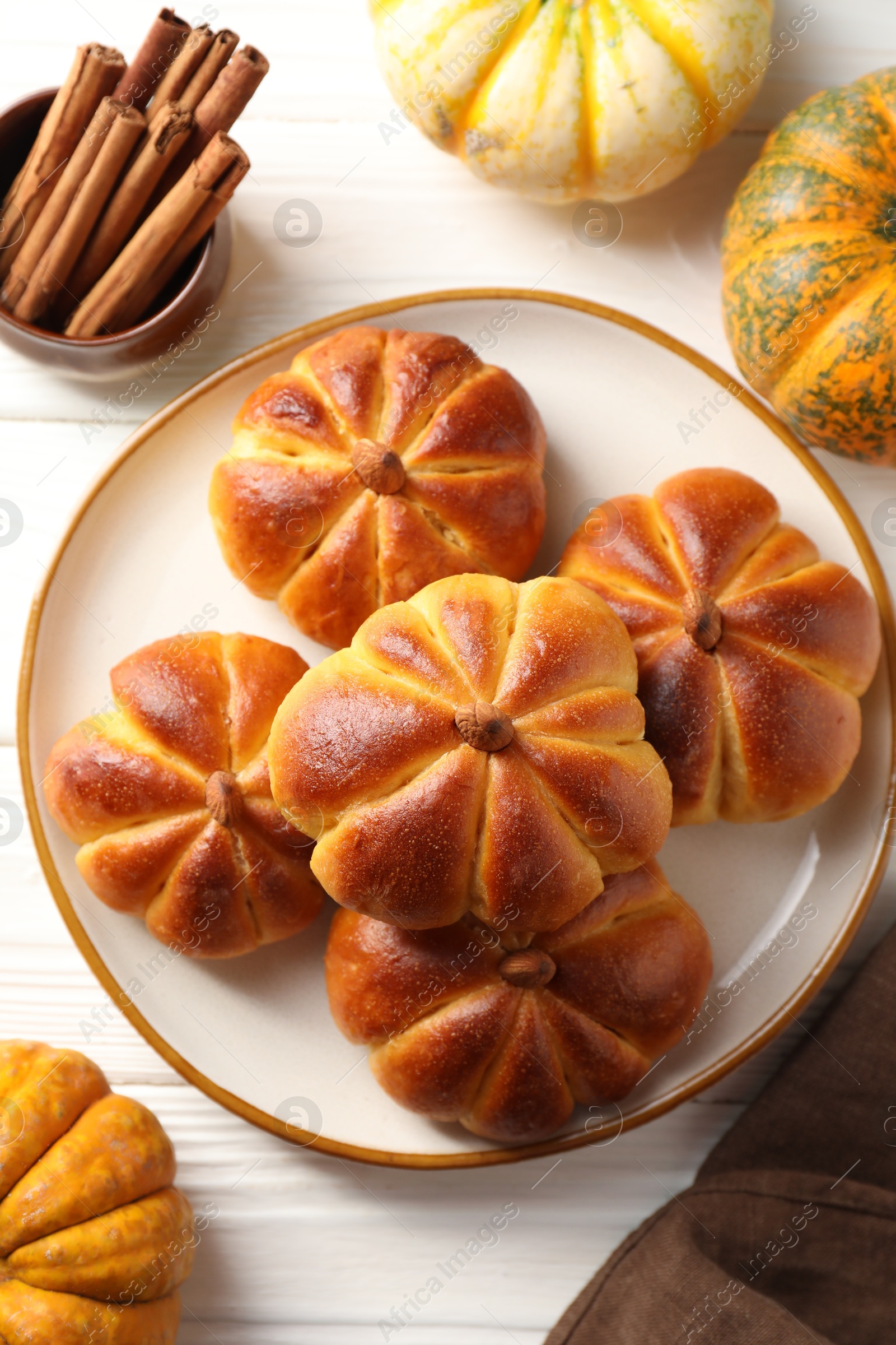 Photo of Tasty pumpkin shaped buns and ingredients on white wooden table, flat lay