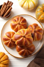 Photo of Tasty pumpkin shaped buns and ingredients on white wooden table, flat lay