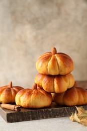 Photo of Tasty pumpkin shaped buns and cinnamon on light grey table, closeup