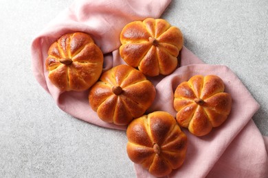 Photo of Tasty pumpkin shaped buns on grey textured table, flat lay