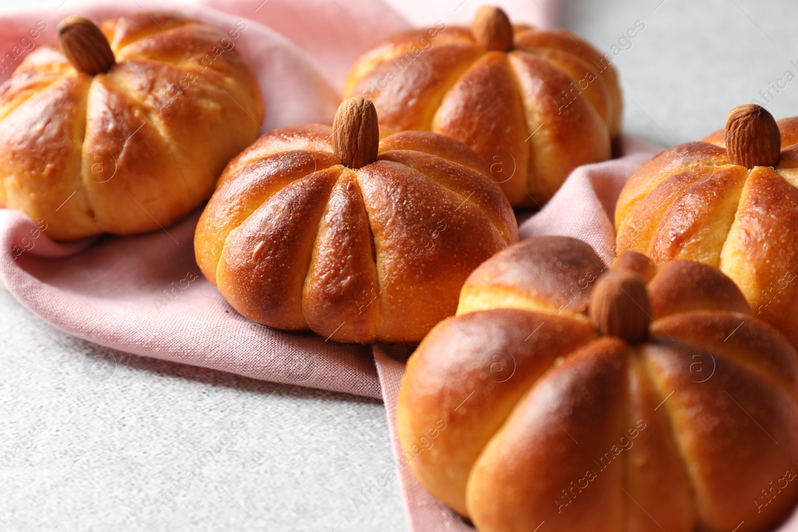 Photo of Tasty pumpkin shaped buns on light textured table, closeup