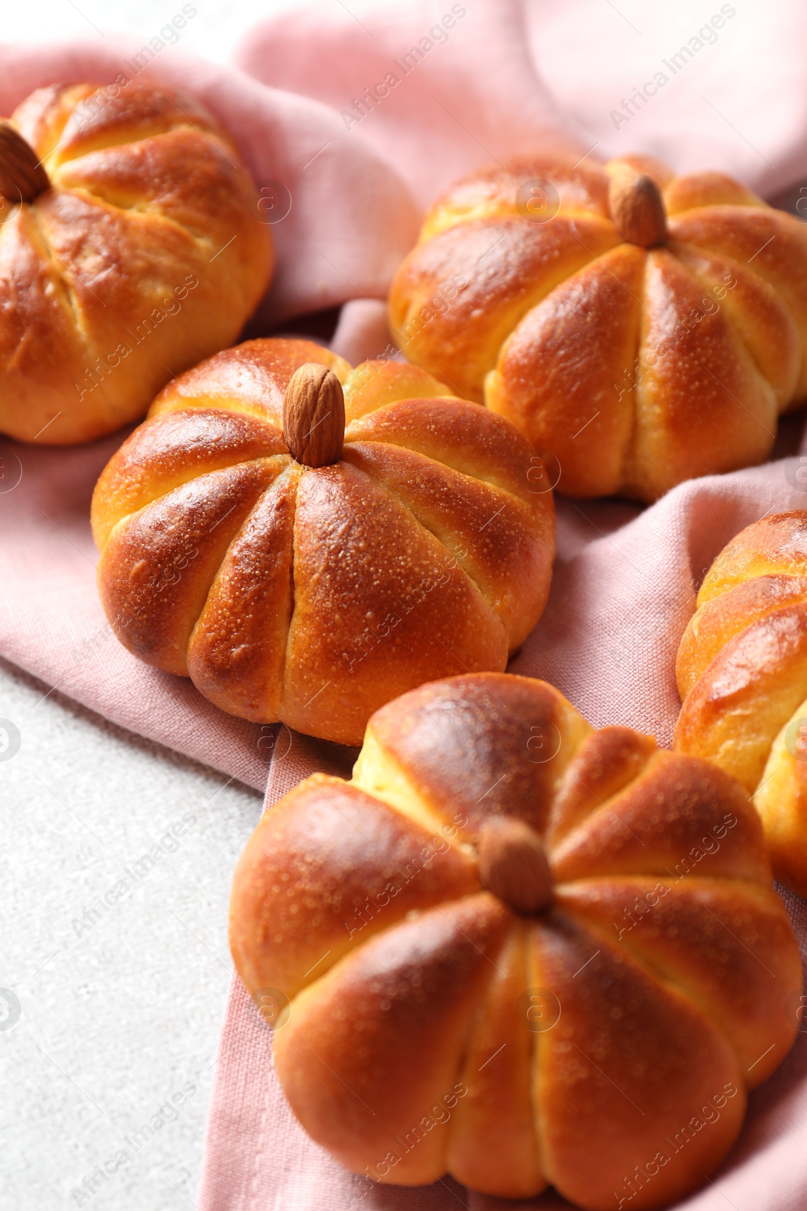 Photo of Tasty pumpkin shaped buns on light textured table, closeup