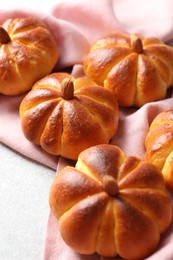 Photo of Tasty pumpkin shaped buns on light textured table, closeup