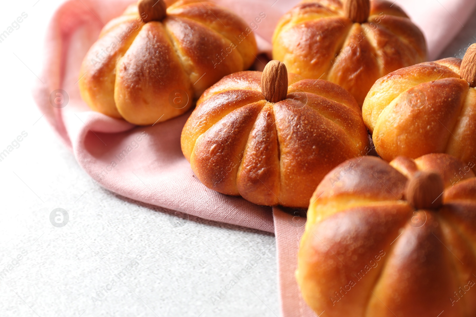 Photo of Tasty pumpkin shaped buns on light textured table, closeup