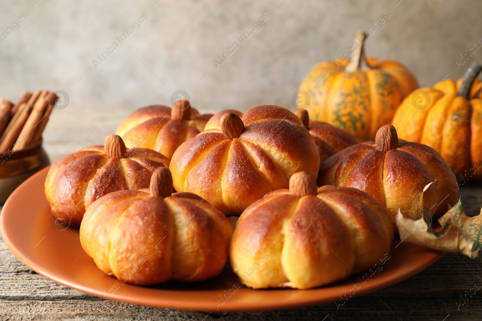 Photo of Tasty pumpkin shaped buns on wooden table, closeup