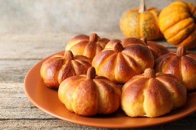 Photo of Tasty pumpkin shaped buns on wooden table, closeup