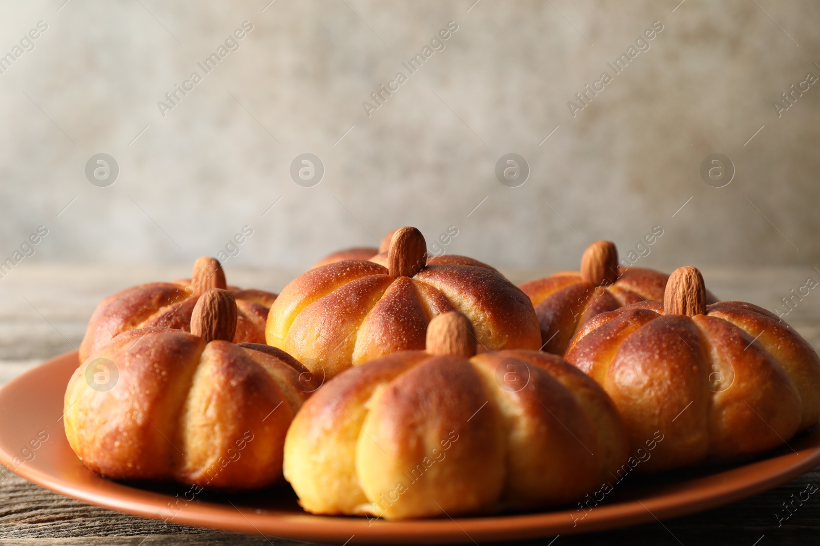 Photo of Tasty pumpkin shaped buns on wooden table, closeup