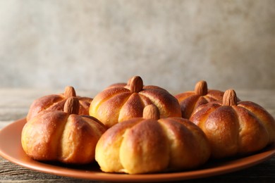 Photo of Tasty pumpkin shaped buns on wooden table, closeup