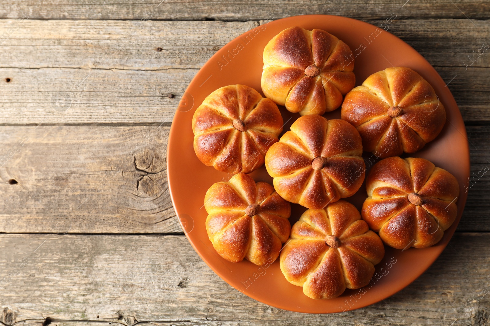 Photo of Tasty pumpkin shaped buns on wooden table, top view. Space for text