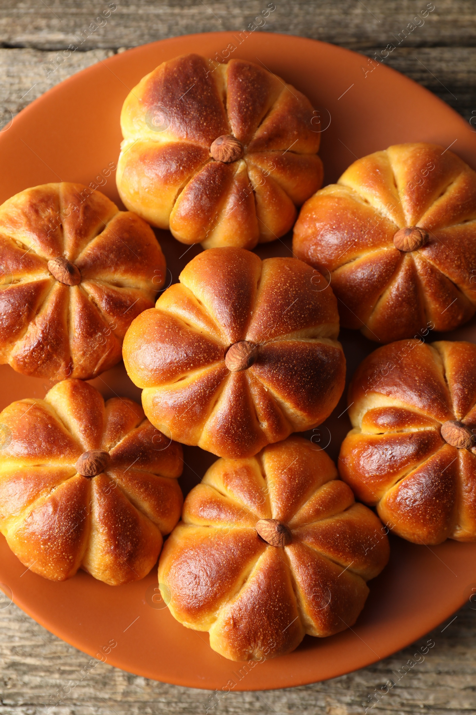 Photo of Tasty pumpkin shaped buns on wooden table, top view