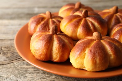 Photo of Tasty pumpkin shaped buns on wooden table, closeup