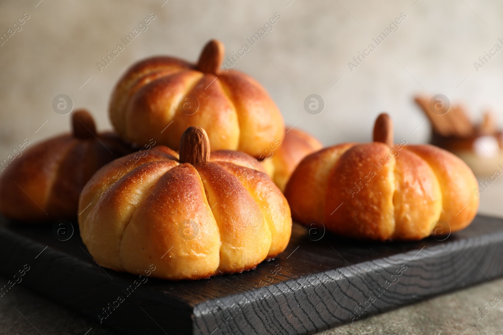 Photo of Tasty pumpkin shaped buns on grey table, closeup