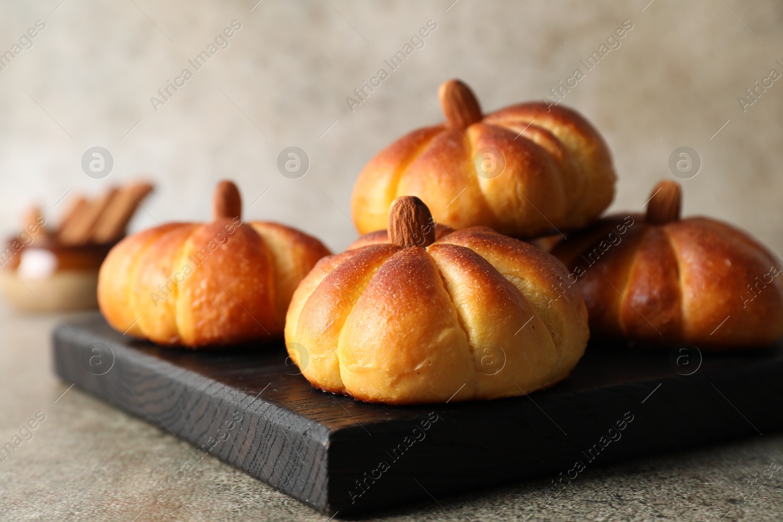 Photo of Tasty pumpkin shaped buns on grey table, closeup