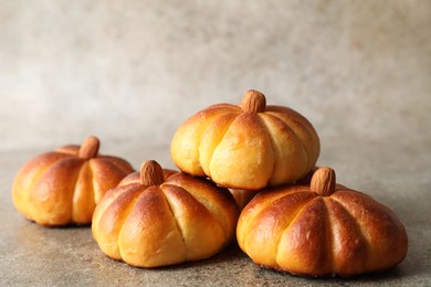 Photo of Tasty pumpkin shaped buns on grey table, closeup