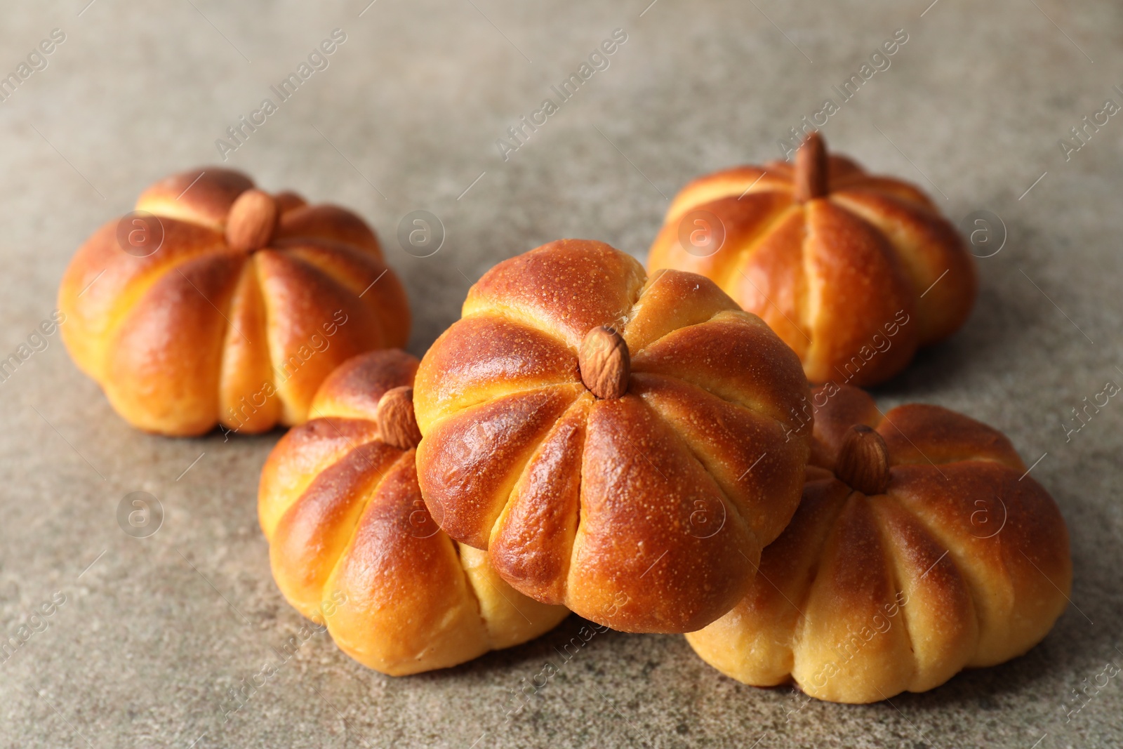 Photo of Tasty pumpkin shaped buns on grey table, closeup