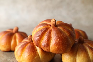 Photo of Tasty pumpkin shaped buns on grey table, closeup