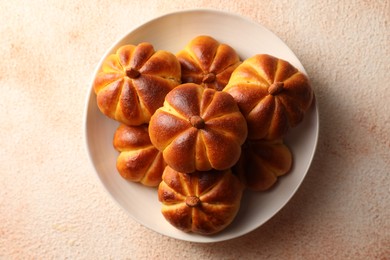 Tasty pumpkin shaped buns on beige textured table, top view