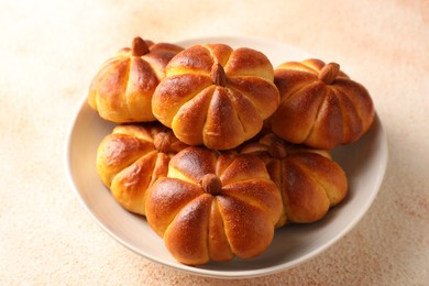 Photo of Tasty pumpkin shaped buns on beige textured table, closeup