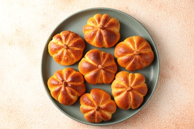 Photo of Tasty pumpkin shaped buns on beige textured table, top view