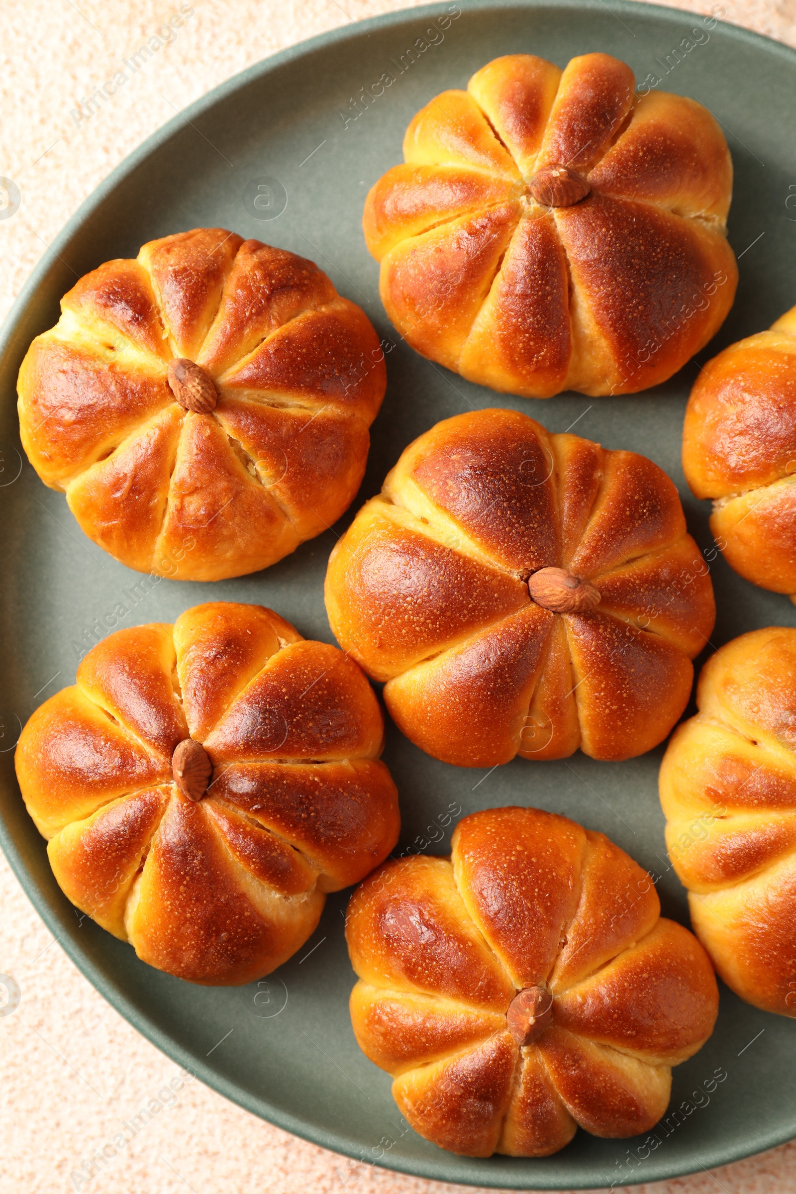 Photo of Tasty pumpkin shaped buns on beige textured table, top view