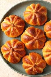 Photo of Tasty pumpkin shaped buns on beige textured table, top view