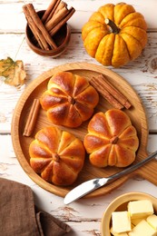 Photo of Tasty pumpkin shaped buns served on old wooden table, flat lay