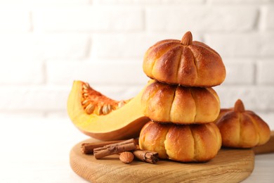 Photo of Tasty pumpkin shaped buns and ingredients on white table, closeup