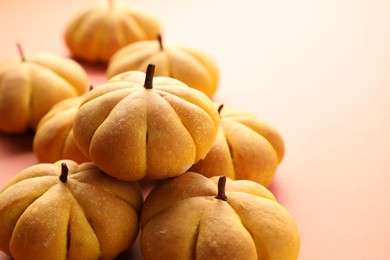 Photo of Pile of tasty pumpkin shaped buns on light background, closeup. Space for text