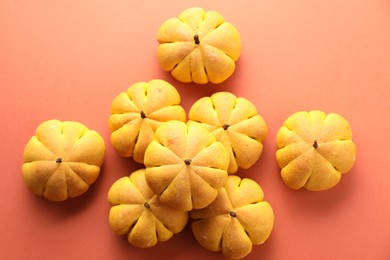 Photo of Tasty pumpkin shaped buns on light red background, above view