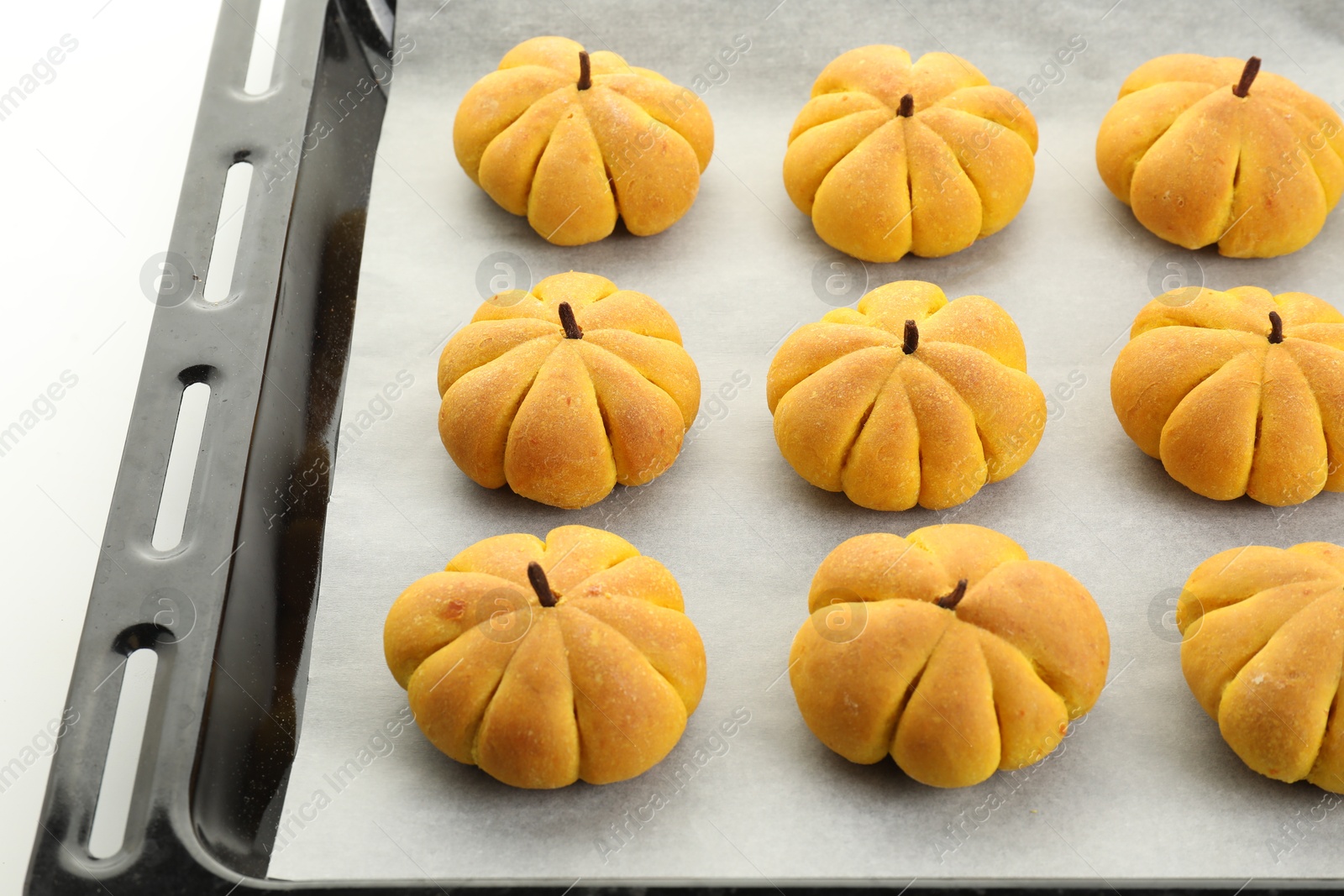 Photo of Baking tray with tasty pumpkin shaped buns on white background, closeup