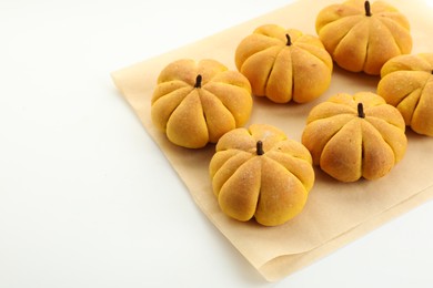 Photo of Parchment with tasty pumpkin shaped buns on white background, closeup. Space for text