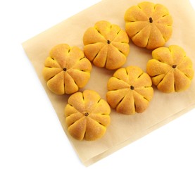 Photo of Parchment with tasty pumpkin shaped buns isolated on white, top view