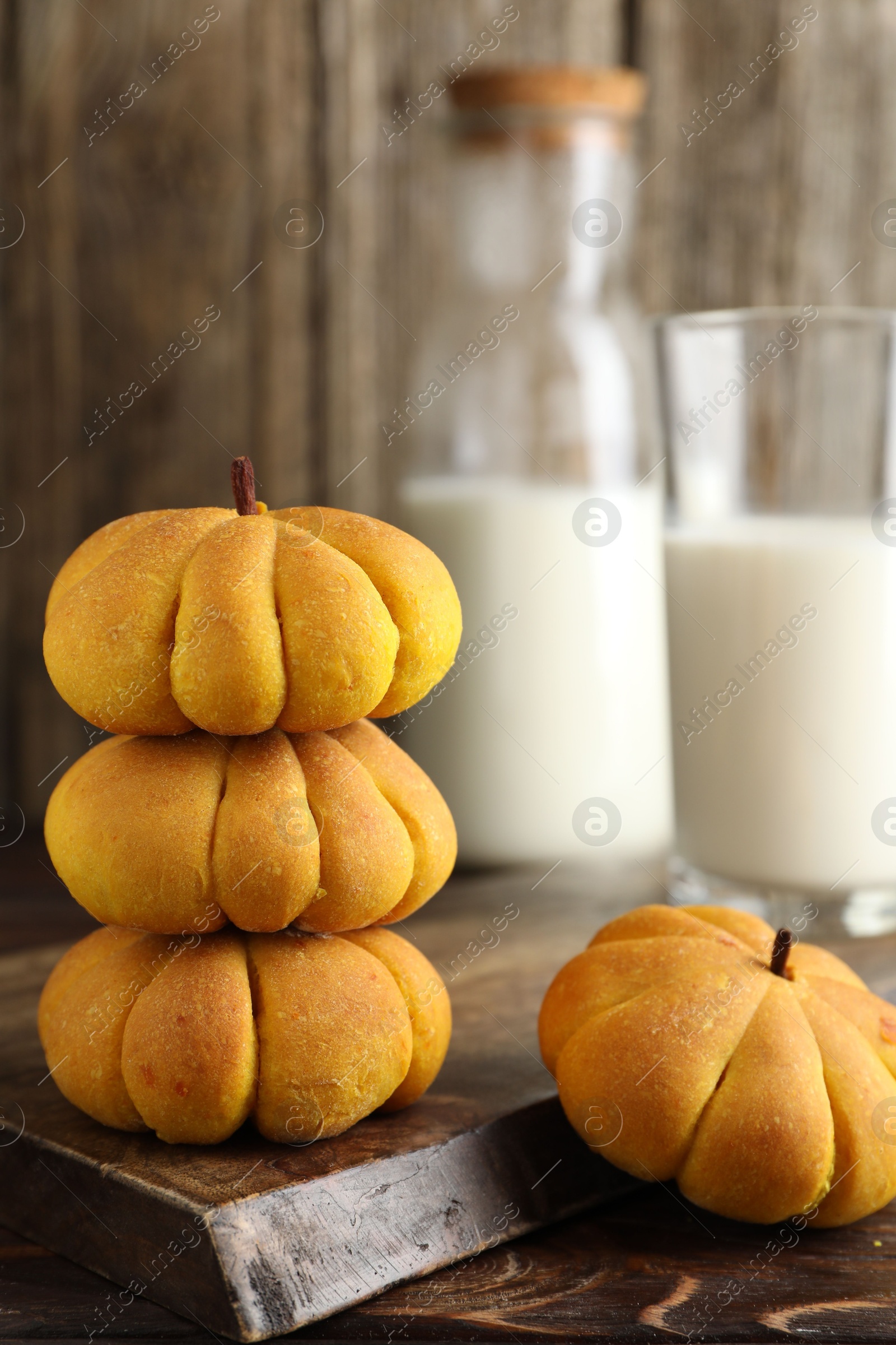 Photo of Tasty pumpkin shaped buns on wooden table