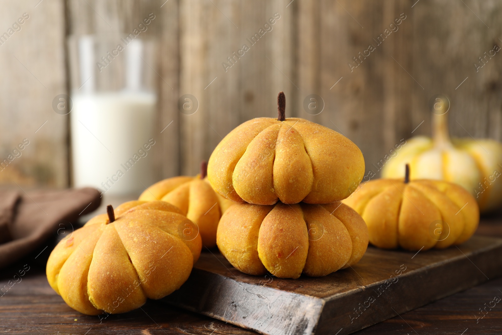 Photo of Tasty pumpkin shaped buns on wooden table, closeup