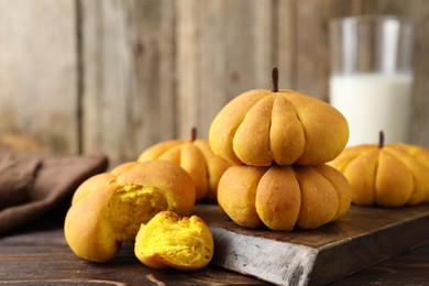 Photo of Tasty pumpkin shaped buns on wooden table, closeup