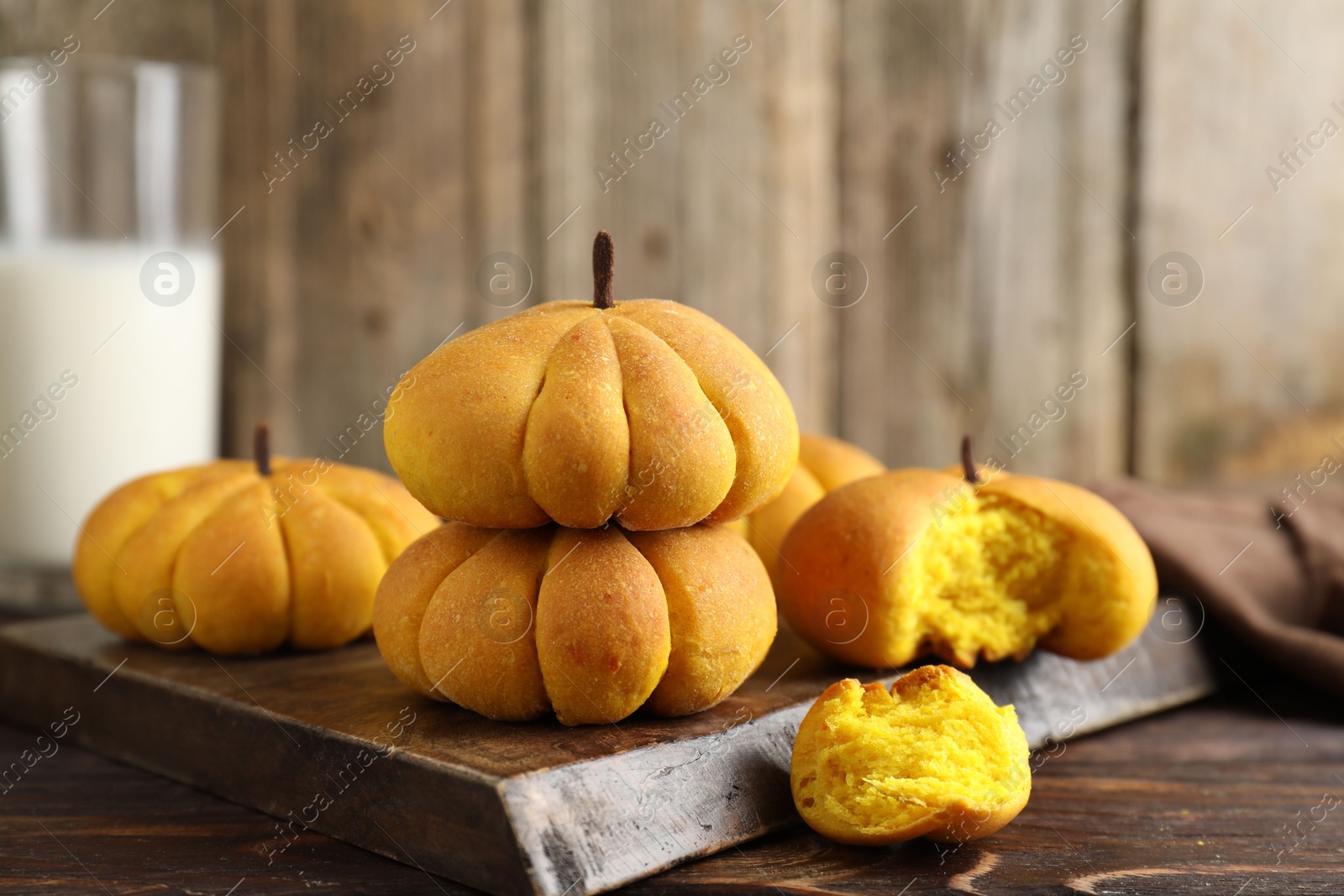 Photo of Tasty pumpkin shaped buns on wooden table, closeup