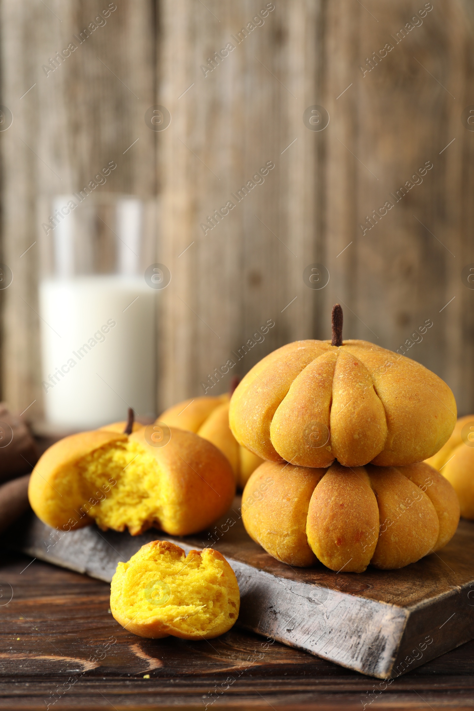 Photo of Tasty pumpkin shaped buns on wooden table