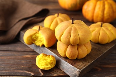 Photo of Tasty pumpkin shaped buns on wooden table, closeup