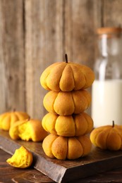 Photo of Stack of tasty pumpkin shaped buns on wooden table, closeup