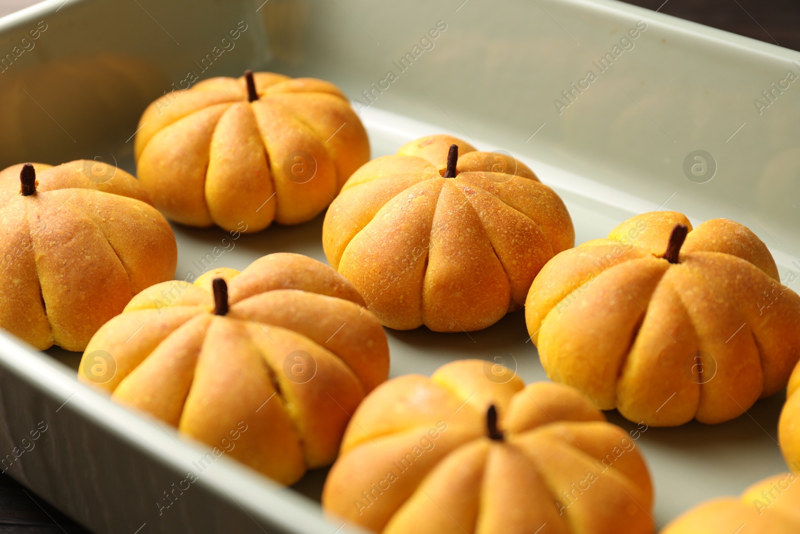 Photo of Tasty pumpkin shaped buns in baking tray, closeup