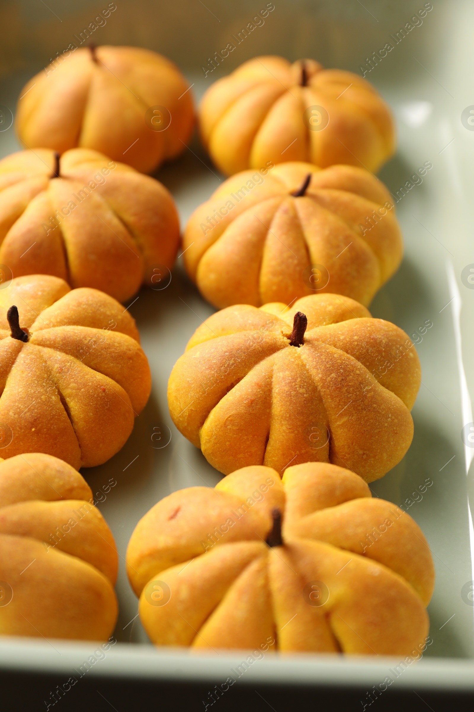 Photo of Tasty pumpkin shaped buns in baking tray, closeup