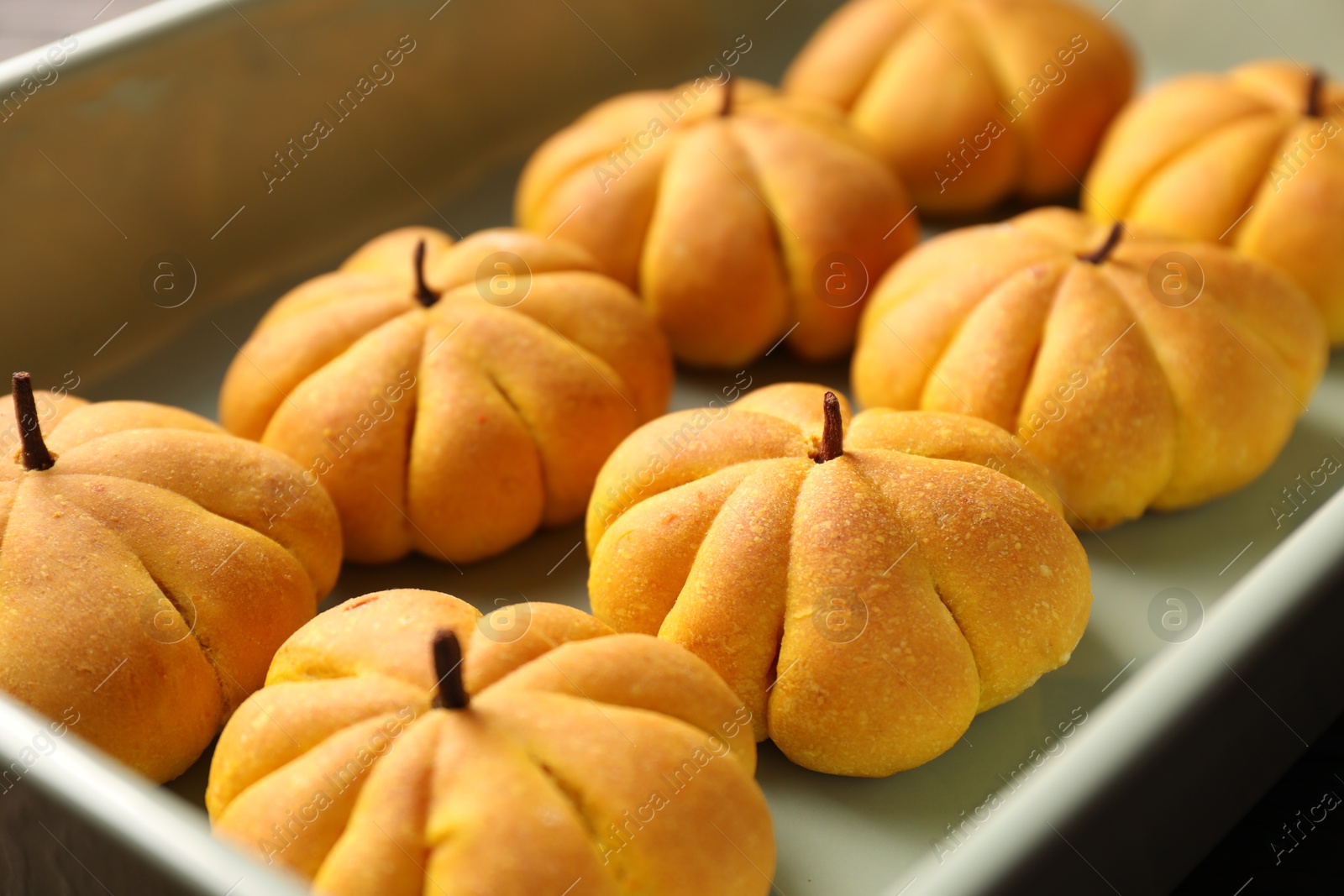 Photo of Tasty pumpkin shaped buns in baking tray, closeup