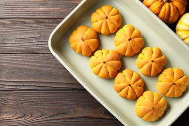 Photo of Baking tray with tasty pumpkin shaped buns on wooden table, top view. Space for text