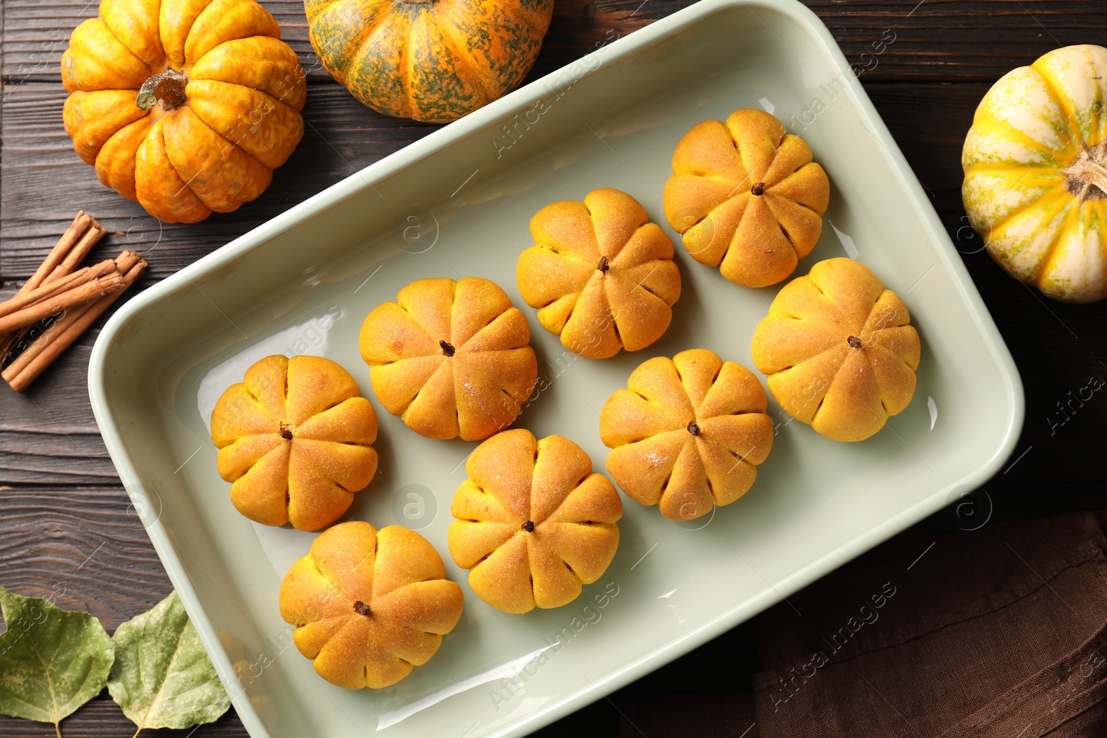 Photo of Flat lay composition with tasty pumpkin shaped buns on wooden table