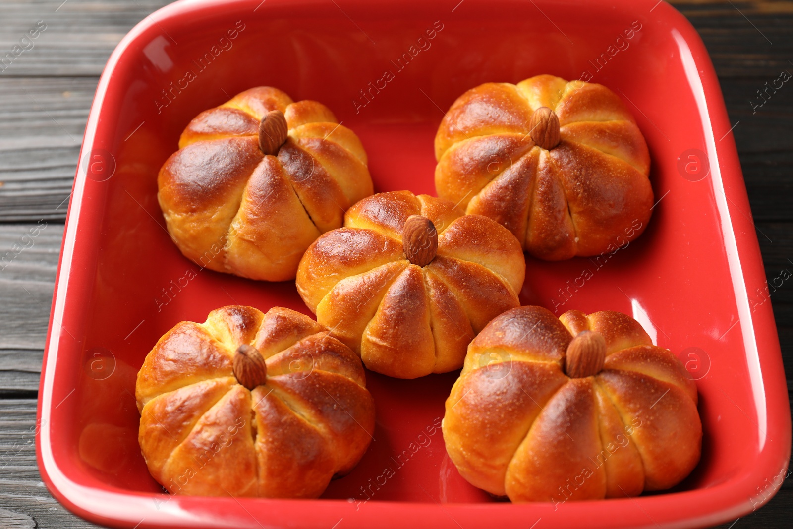 Photo of Baking tray with tasty pumpkin shaped buns on wooden table, closeup