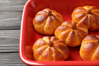 Photo of Baking tray with tasty pumpkin shaped buns on wooden table, closeup