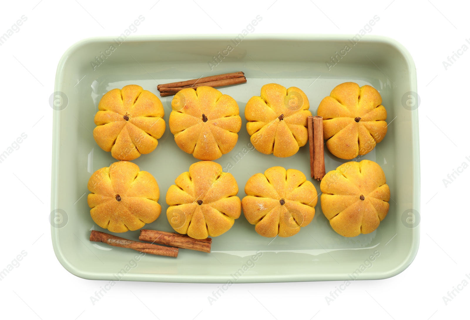 Photo of Baking tray with tasty pumpkin shaped buns and cinnamon sticks isolated on white, top view